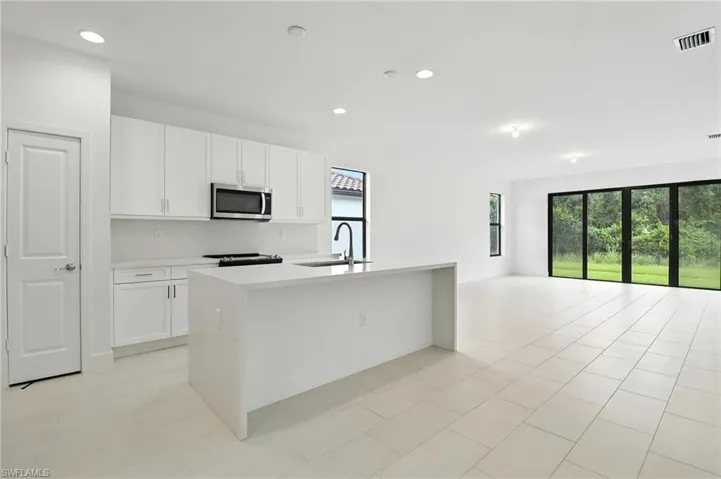 Kitchen with stainless steel microwave, healthy amount of natural light, electric range, light countertops, and recessed lighting