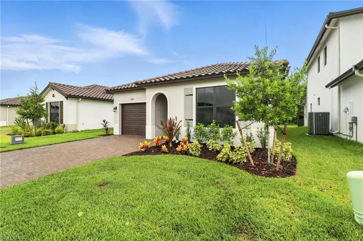 Mediterranean / spanish-style house featuring decorative driveway, stucco siding, a front lawn, a garage, and a tiled roof