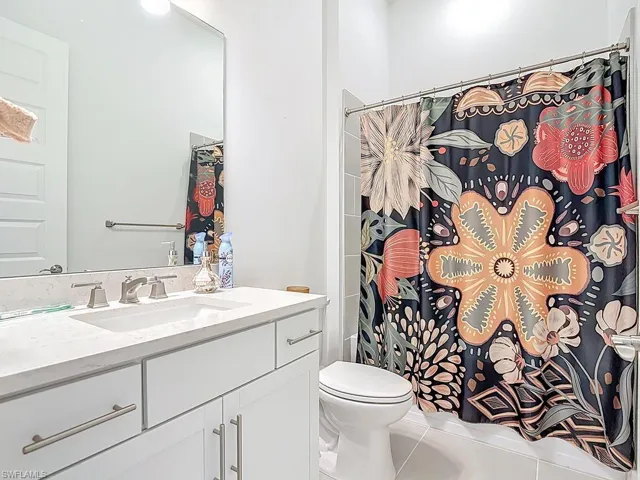 Bathroom with vanity, a shower with shower curtain, and tile patterned floors