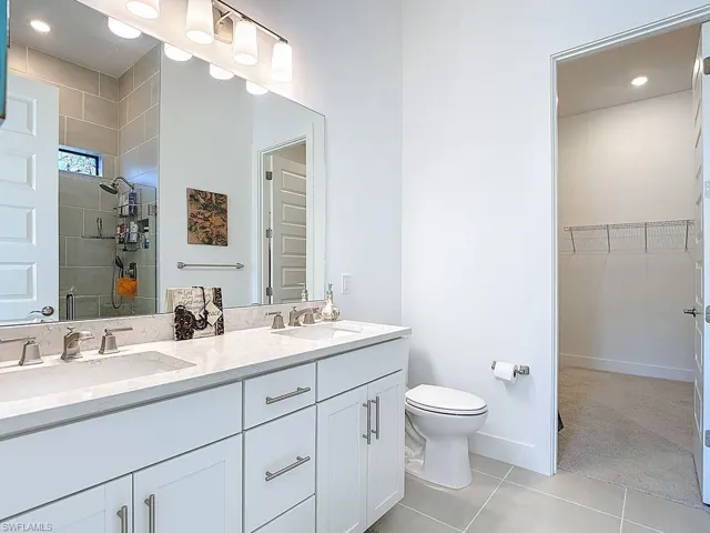 Full bathroom featuring a walk in closet, double vanity, a shower stall, recessed lighting, and light carpet