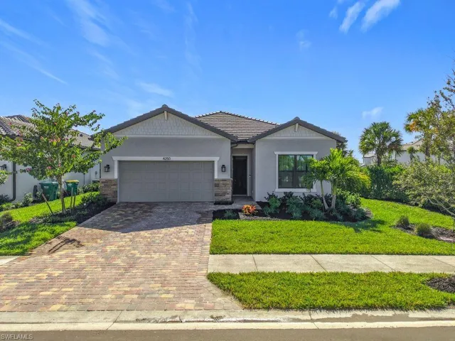 Ranch-style house with decorative driveway, stone siding, a garage, stucco siding, and a front yard