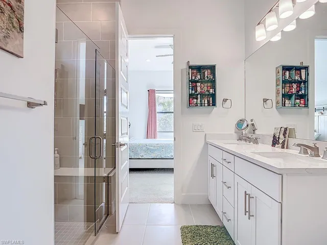 Full bath with ensuite bath, double vanity, a shower stall, light carpet, and light tile patterned floors