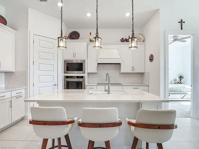 Kitchen featuring a kitchen bar, light tile patterned flooring, and white cabinets