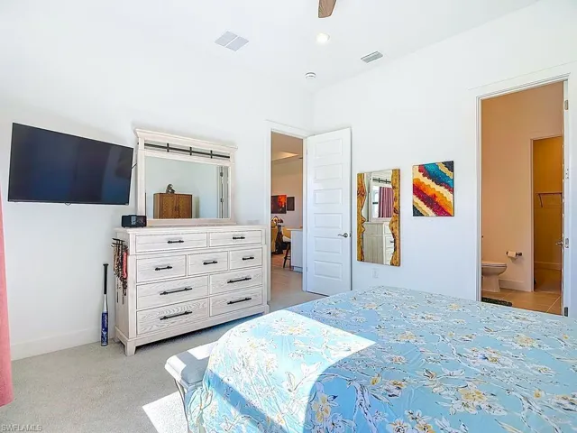 Bedroom featuring ceiling fan, light colored carpet, and connected bathroom