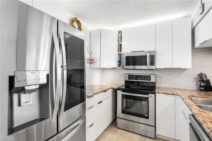 Stainless appliances, new white cabinetry, and granite counters.