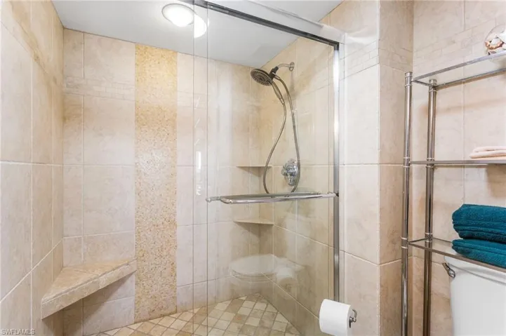 Walk-in custom tiled shower with heavy glass shower doors.
