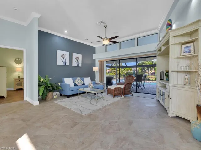 Living area with ornamental molding, baseboards, and a ceiling fan