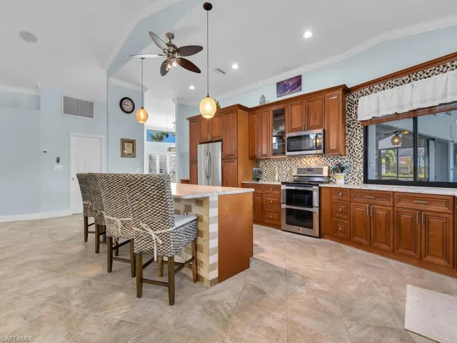 Kitchen featuring backsplash, visible vents, brown cabinetry, ceiling fan, and appliances with stainless steel finishes