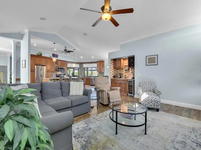 Living area with light wood-style flooring, a ceiling fan, ornamental molding, and wine cooler