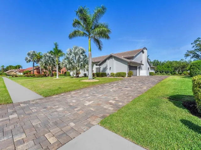 View of front of property with stucco siding, driveway, an attached garage, a front lawn, and a tiled roof
