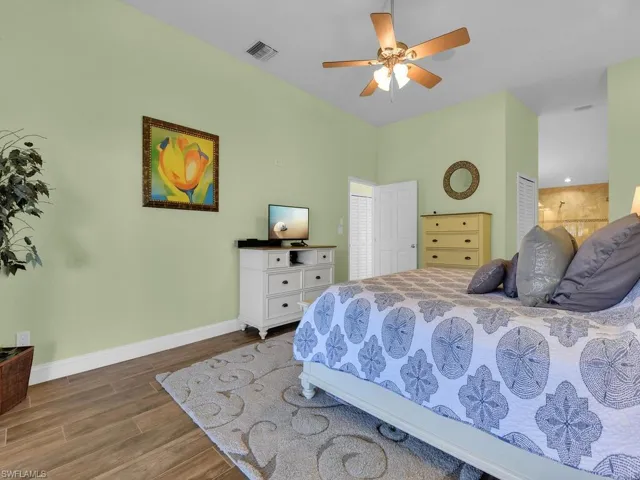Bedroom featuring wood finished floors, baseboards, a ceiling fan, and visible vents