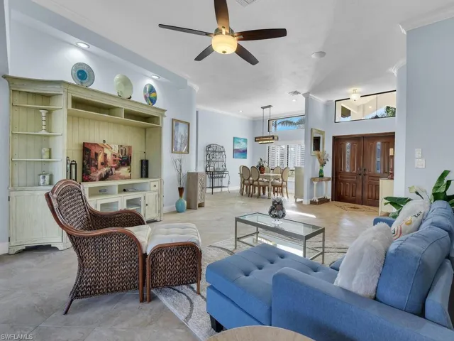 Living room featuring ornamental molding, ceiling fan, and baseboards