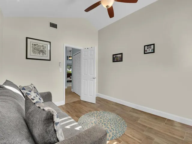 Living area with ceiling fan, visible vents, wood tiled floor, lofted ceiling, and baseboards
