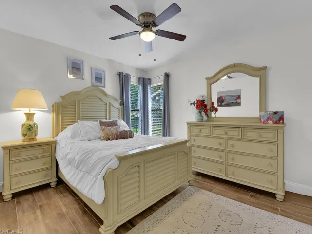 Bedroom with baseboards, wood tiled floor, and a ceiling fan