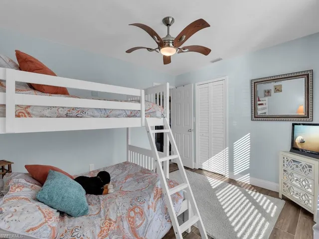 Bedroom with a closet, a ceiling fan, visible vents, wood finished floors, and baseboards