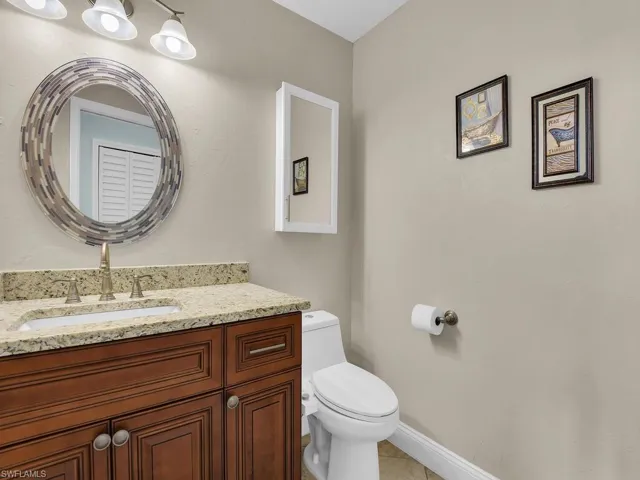 Half bathroom with toilet, vanity, and baseboards