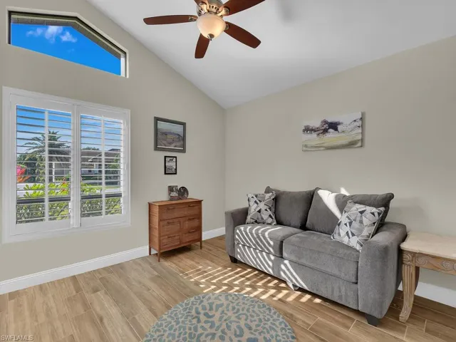 Living area with plenty of natural light, wood finish floors, and lofted ceiling