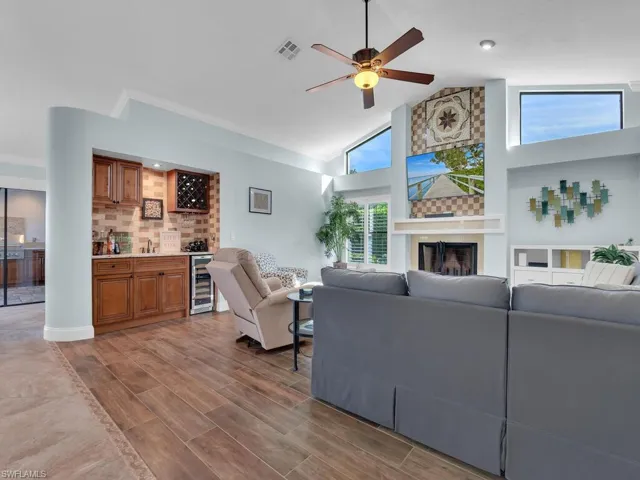 Living area featuring a ceiling fan, visible vents, wood finished floors, beverage cooler, and indoor bar