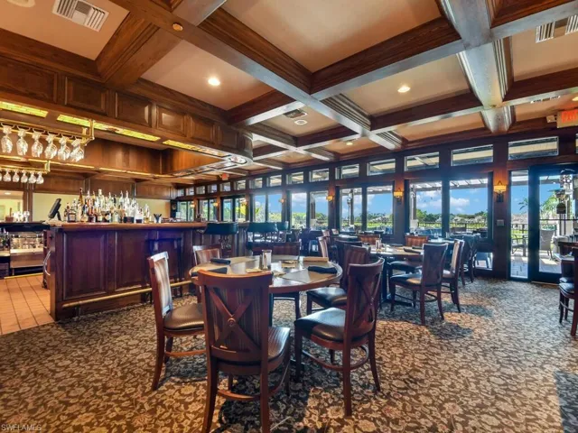 Dining room with a bar, visible vents, beam ceiling, and carpet floors