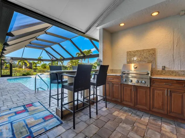 View of patio / terrace featuring outdoor wet bar, grilling area, exterior kitchen, an outdoor pool, and a lanai