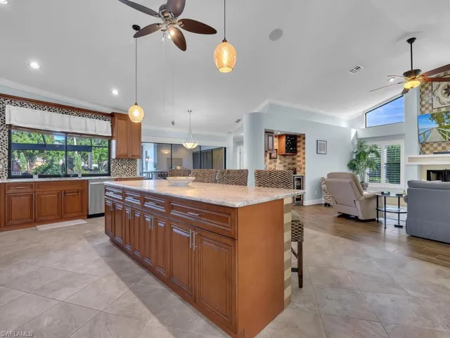 Kitchen featuring open floor plan, a kitchen bar, stainless steel dishwasher, and a ceiling fan