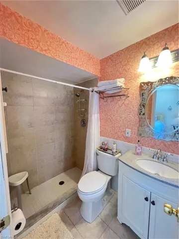 Bathroom with walk in shower, tile flooring, toilet, and vanity with extensive cabinet space