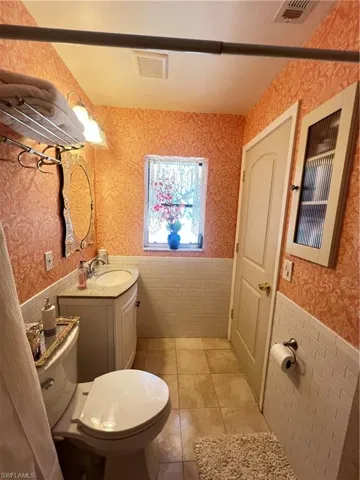 Bathroom featuring tile flooring, vanity, toilet, and tile walls