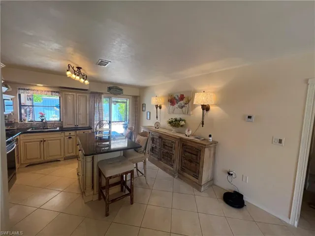 Kitchen with light tile floors, sink, a breakfast bar, and a kitchen island