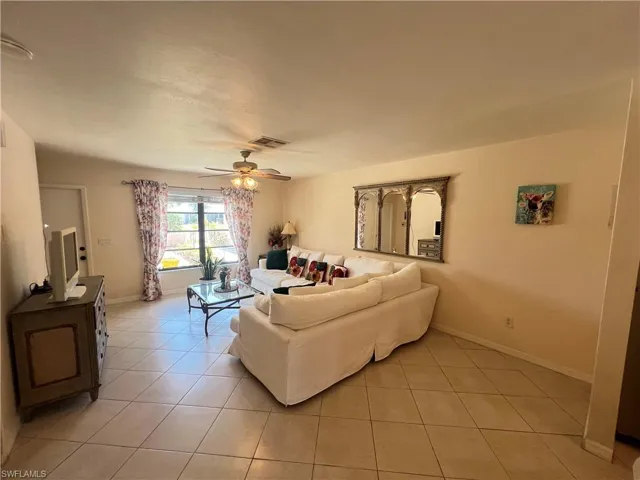 Living room with ceiling fan and light tile floors