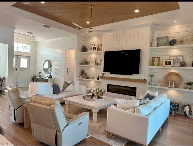 Living room with wood ceiling, wooden walls, and built in features
