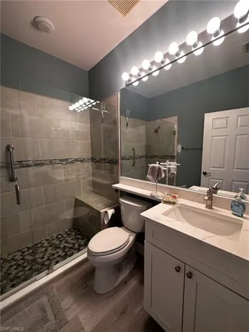 Bathroom with wood finished floors, a stall shower, and vanity
