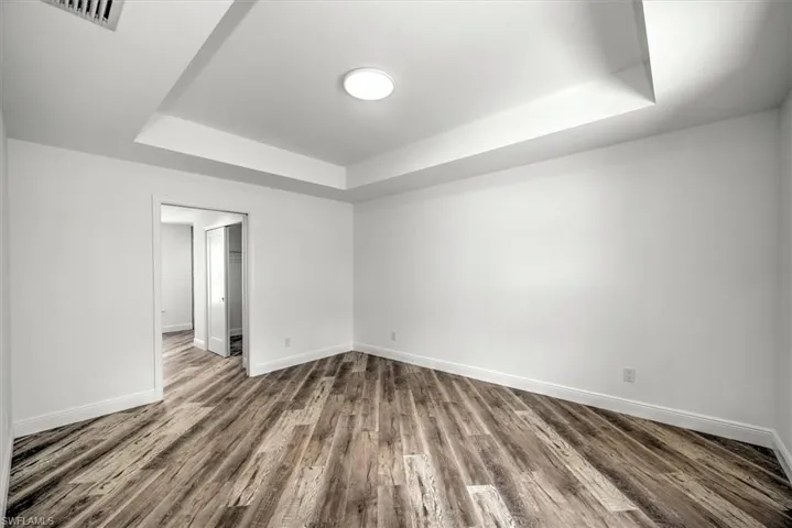 Master bedroom with a tray ceiling. There is a pocket sliding door that separates the closets and the master bath.