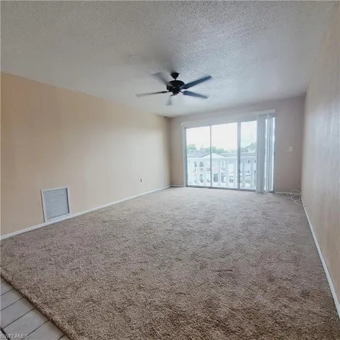 Unfurnished room with a textured ceiling, light colored carpet, and a ceiling fan
