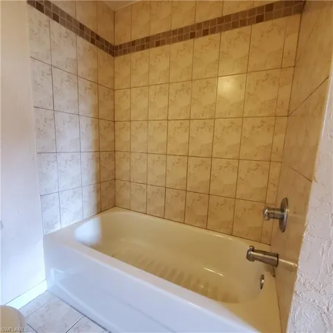 Full bath featuring tile patterned flooring and tub / shower combination