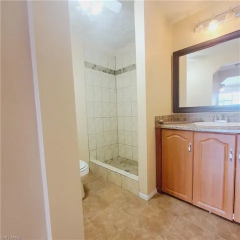 Bathroom featuring a stall shower, vanity, light tile patterned floors, a textured ceiling, and backsplash