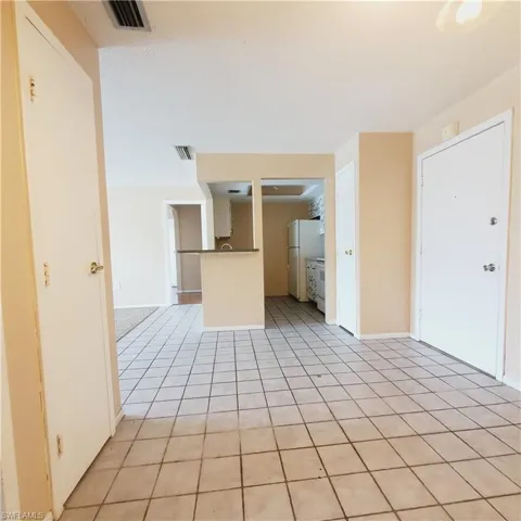 Unfurnished living room featuring light tile patterned floors and baseboards