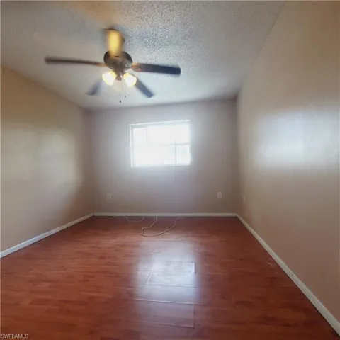 Unfurnished room with wood finished floors, a textured ceiling, and ceiling fan