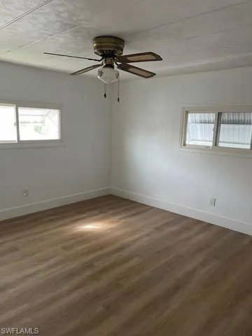 Spare room with dark hardwood / wood-style floors, plenty of natural light, and ceiling fan