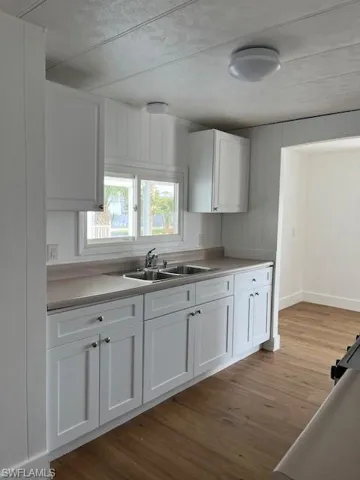 Kitchen with white cabinets, light wood-type flooring, and sink