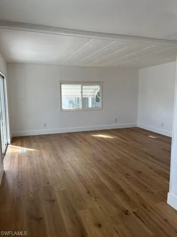 Spare room featuring beam ceiling and dark hardwood / wood-style floors