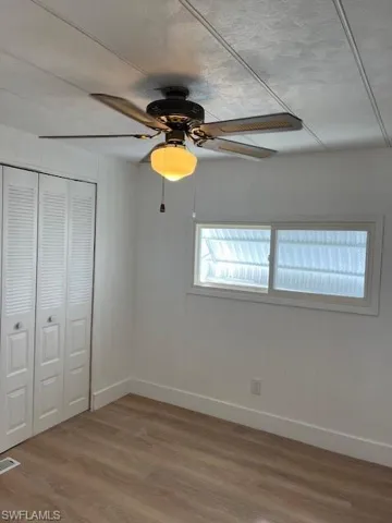 Unfurnished bedroom with hardwood / wood-style floors, ceiling fan, a textured ceiling, and a closet
