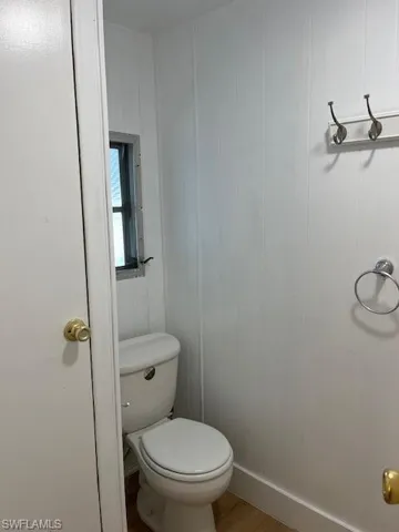 Bathroom with hardwood / wood-style floors, toilet, and wooden walls