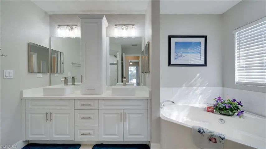 Bathroom with double vanity, a bath, and plenty of natural light