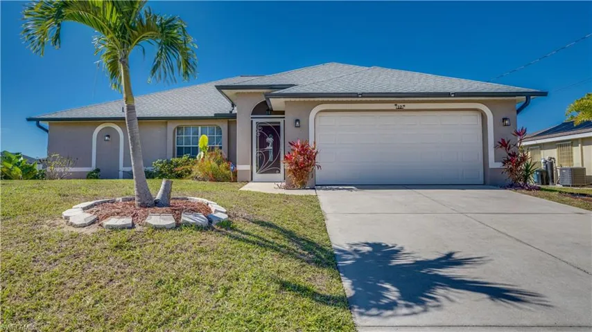 Single story home with stucco siding, a front lawn, and driveway
