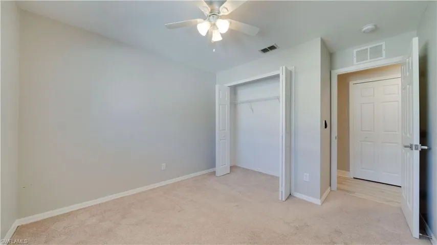 Unfurnished bedroom featuring light colored carpet, a closet, and ceiling fan