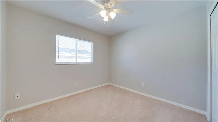 Carpeted empty room featuring baseboards and ceiling fan