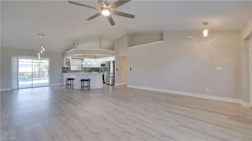 Unfurnished living room with high vaulted ceiling, ceiling fan, and light wood-type flooring