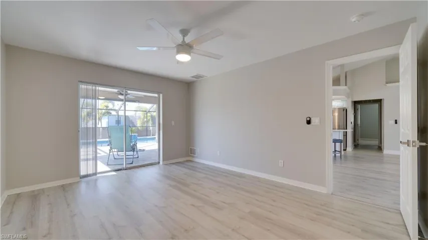 Empty room featuring light wood-type flooring, a sunroom, and a ceiling fan