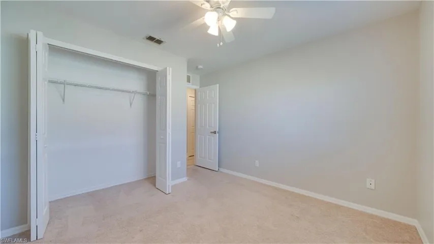 Unfurnished bedroom with light colored carpet, a ceiling fan, and a closet