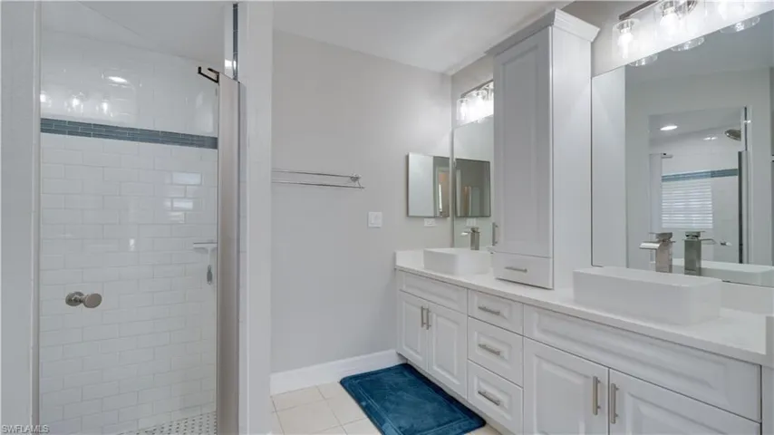 Bathroom with double vanity, a stall shower, and light tile patterned floors